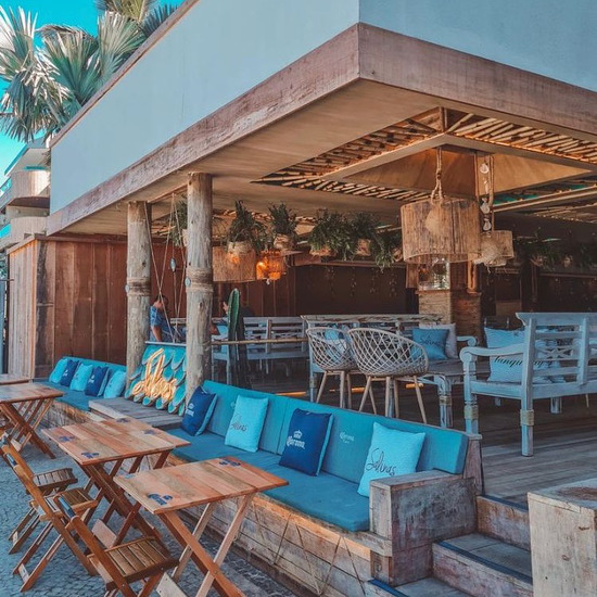 Lounge externo com mesas de madeira e almofadas azuis